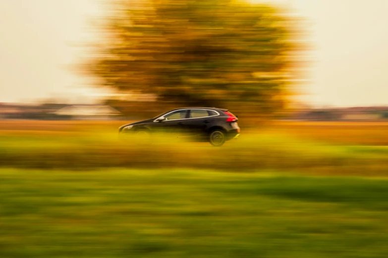 a car traveling through the countryside with an autumn tree in the background