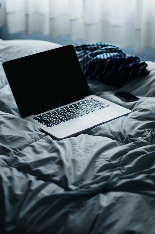 an open laptop computer is on top of a bed