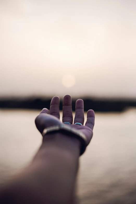 hand with small ring on palm near body of water