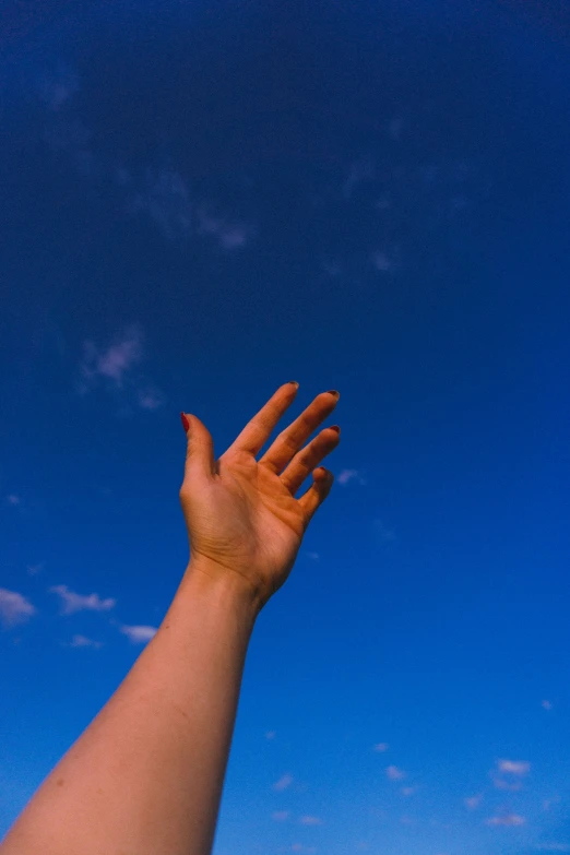 someone's arm reaching into the sky while holding their hand out for a kite