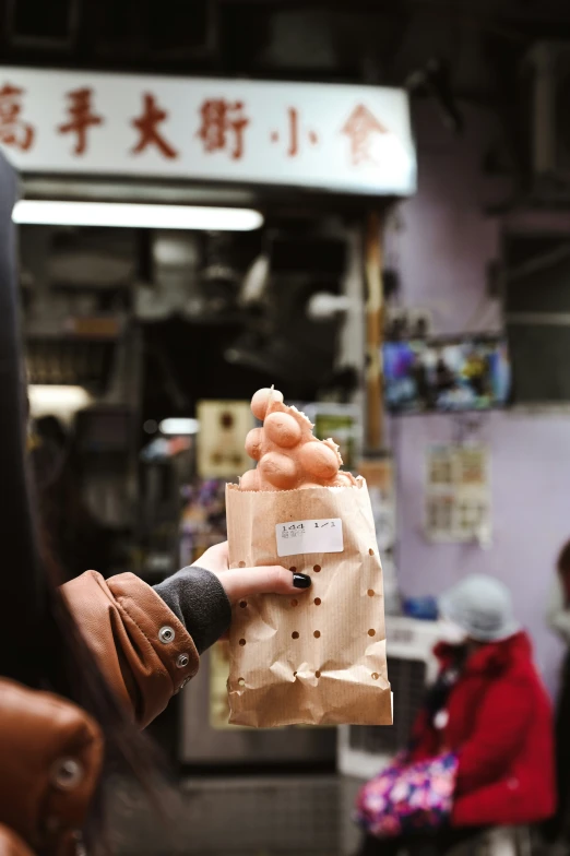 the woman holds a brown bag in her hand