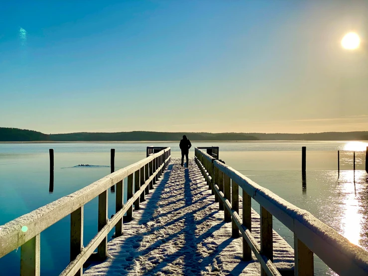 a person on a wooden pier in the snow