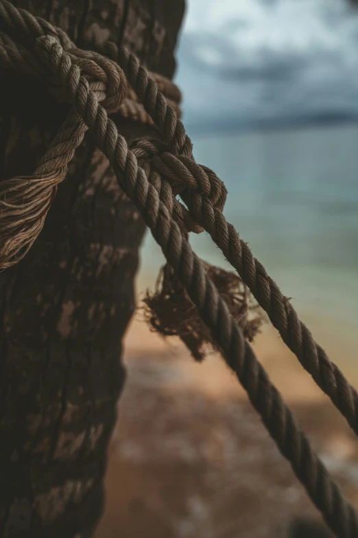 a rope attached to the outside of an old wooden structure with the sea in the background