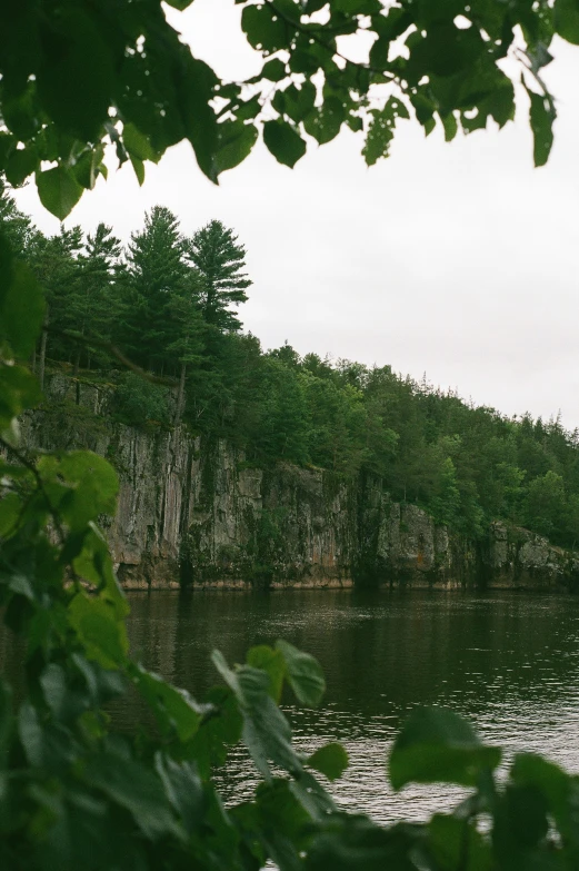 a boat sails on the water near a large rock cliff