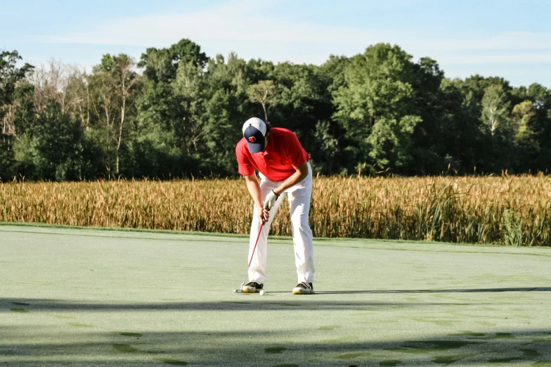 the person in red is hitting the golf ball