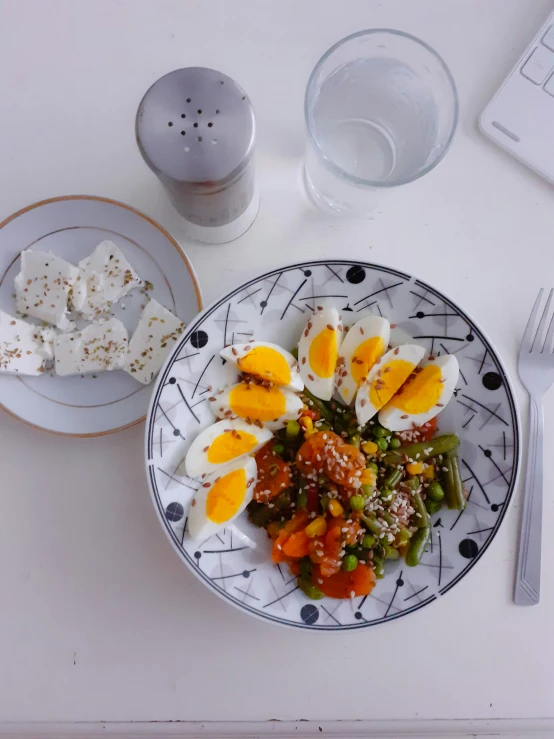 an overhead view of a plate of food with hard boiled eggs, green beans and cheese