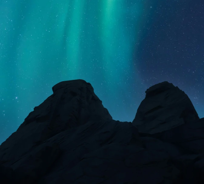 a silhouette of a person on a mountain under the stars