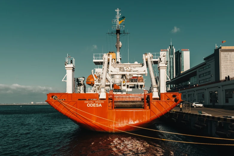 an orange and white cargo ship at dock