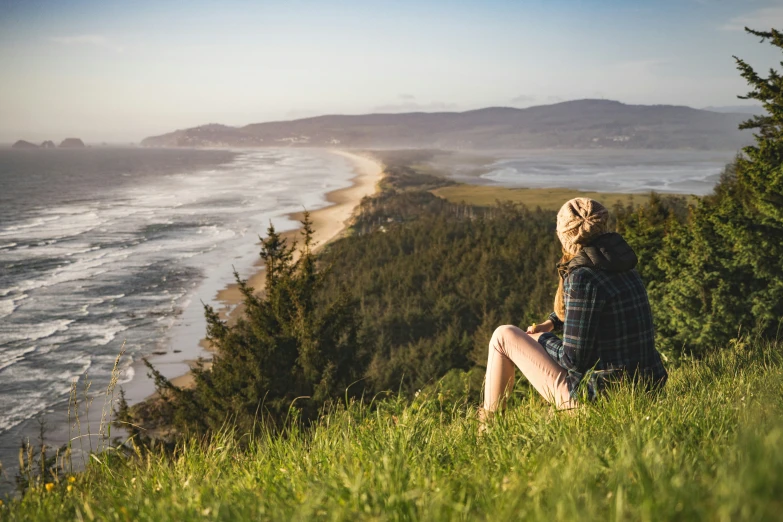 a woman sitting on top of a lush green hillside