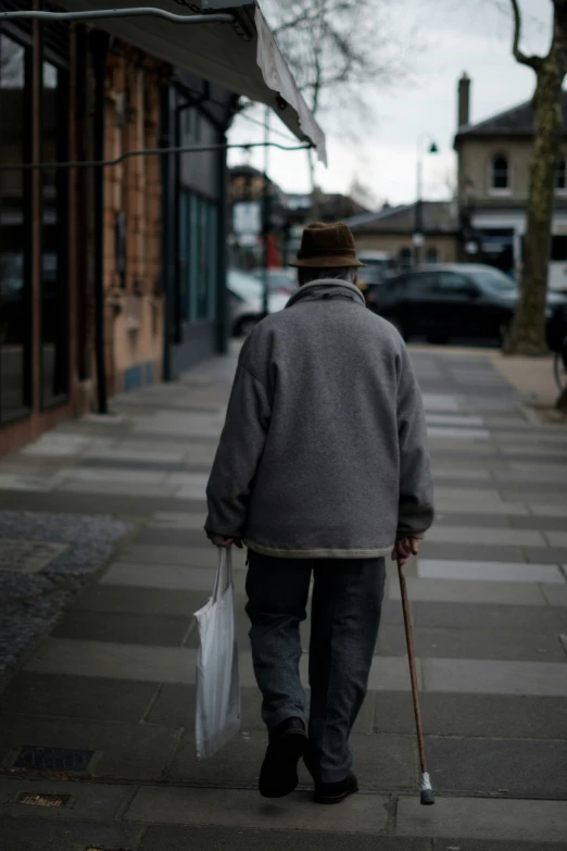 an old man walking down the street with a cane