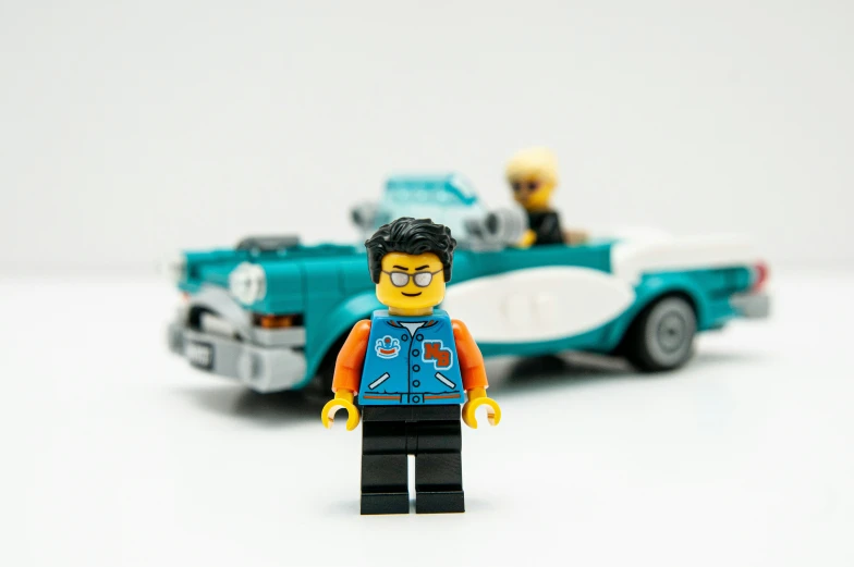 two lego figures in different colors next to a car