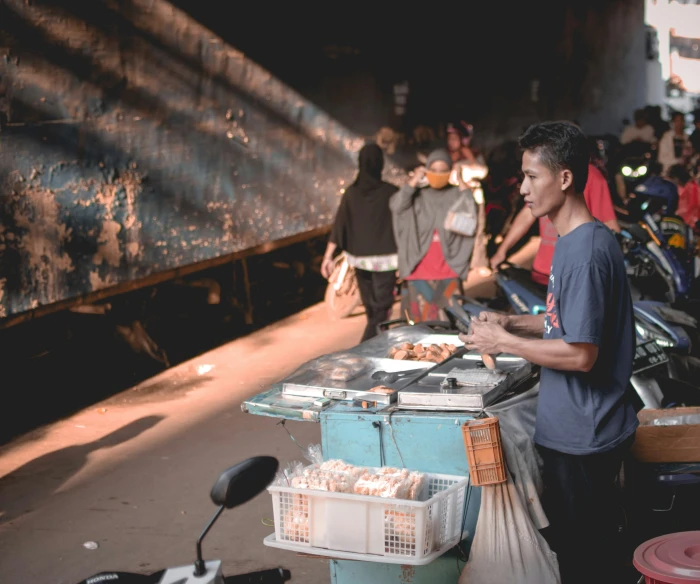 an asian man waits on the side of a street at night