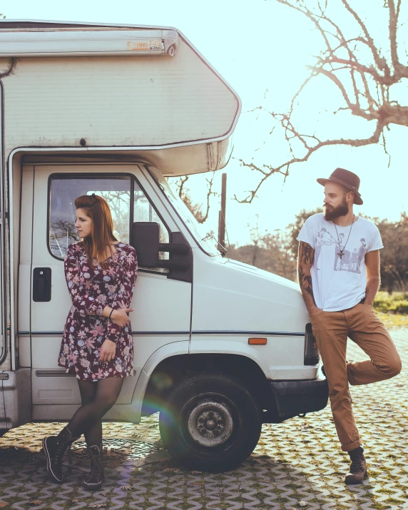 a man and woman standing outside an old van