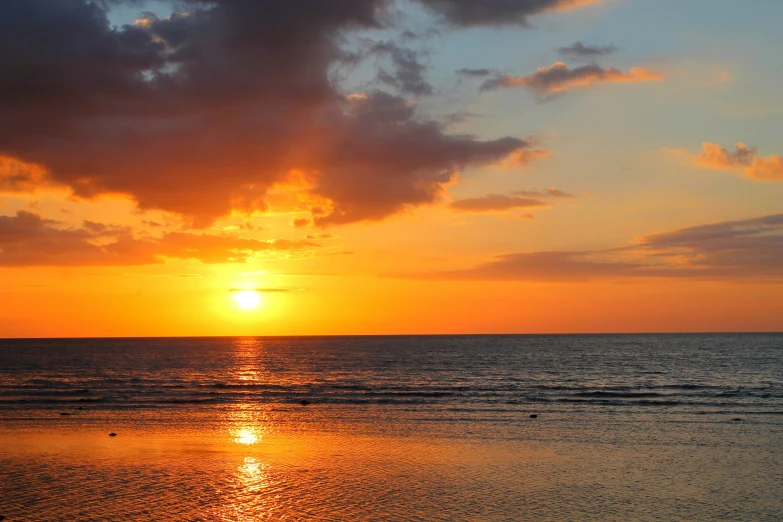 a sunset on a calm beach, taken from the water