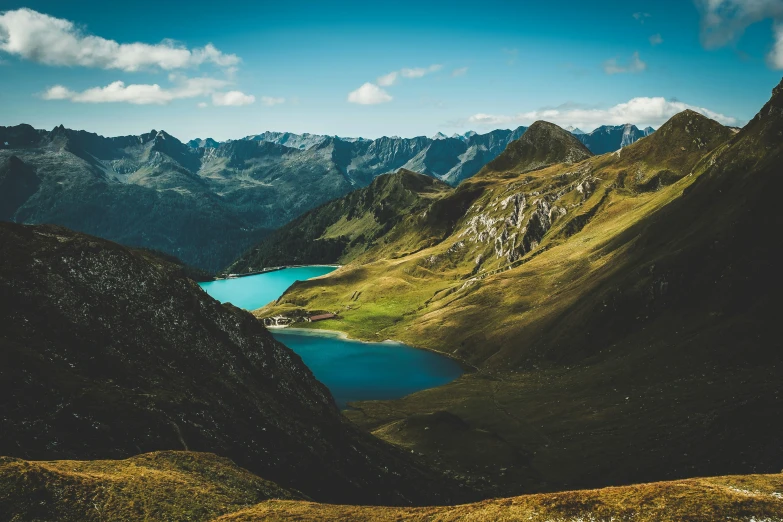 a mountain scene, with blue water in the center and green grass to the foreground