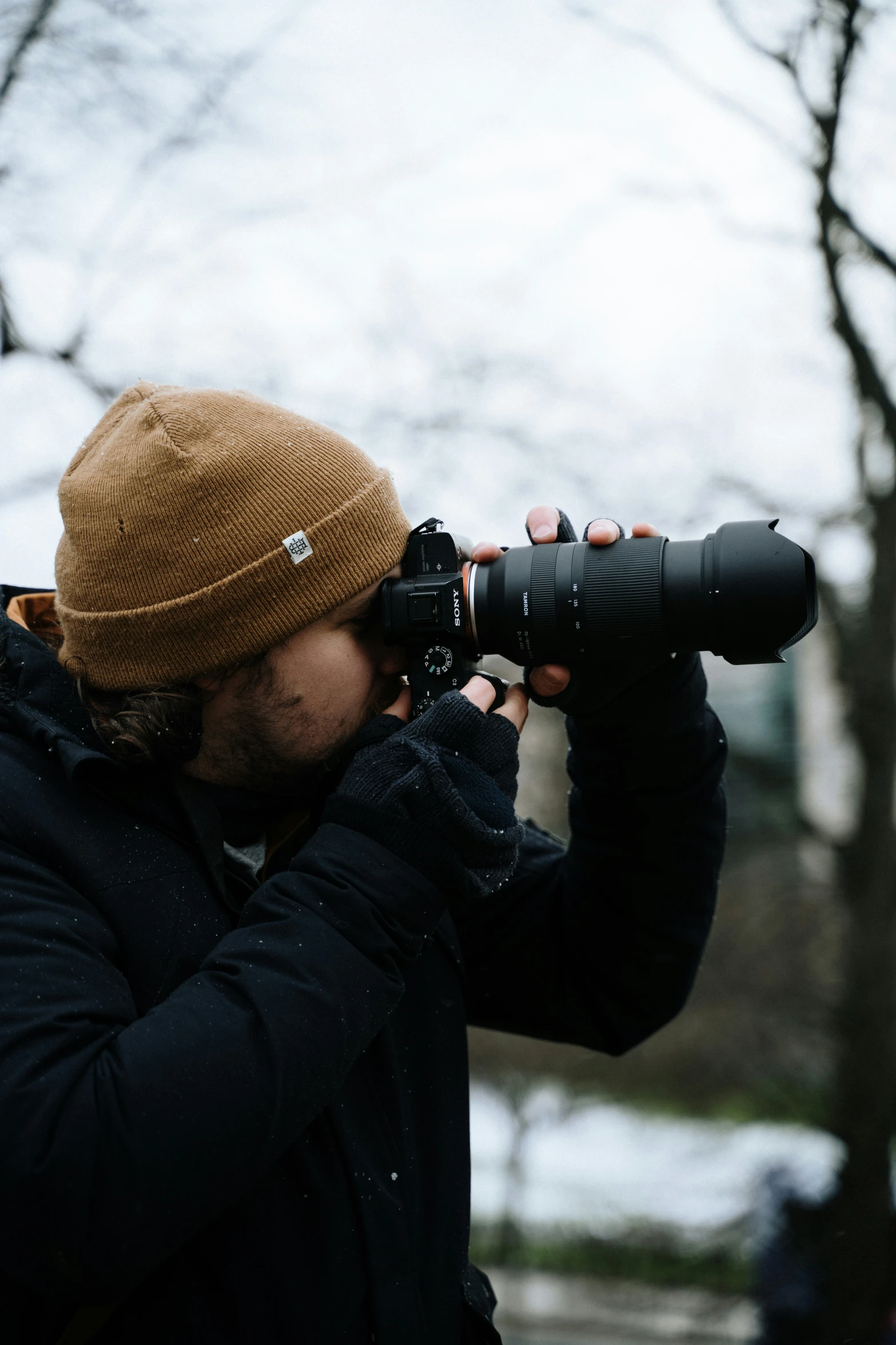 a person holding up a camera with a hat on their head