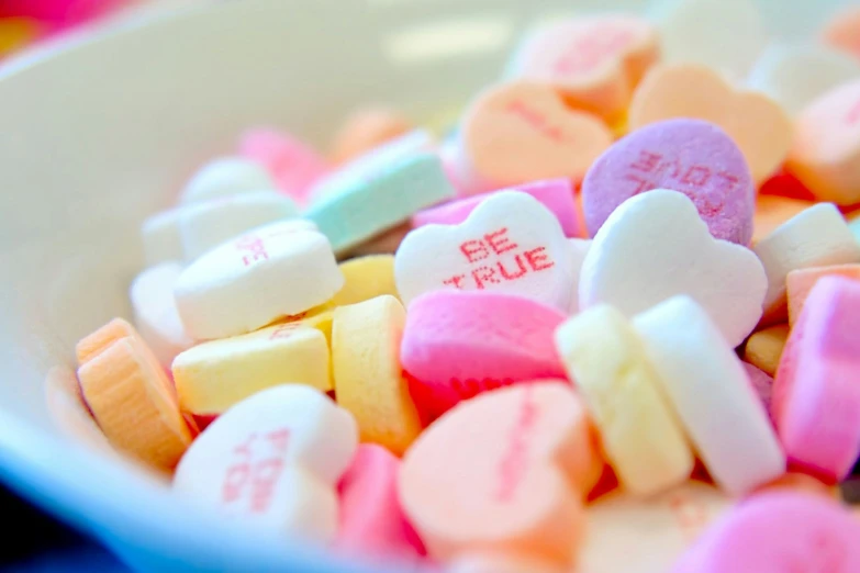 hearts shaped candy are in a white bowl