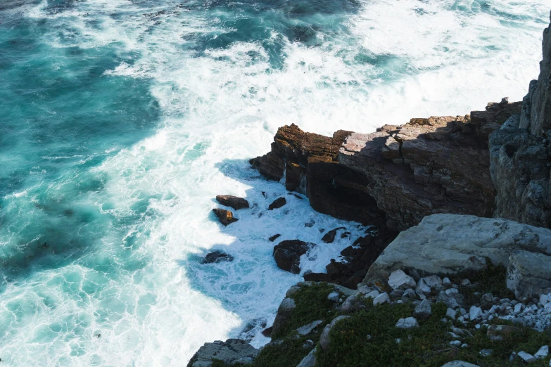 the cliffs overlook a green, rocky, choppy shoreline