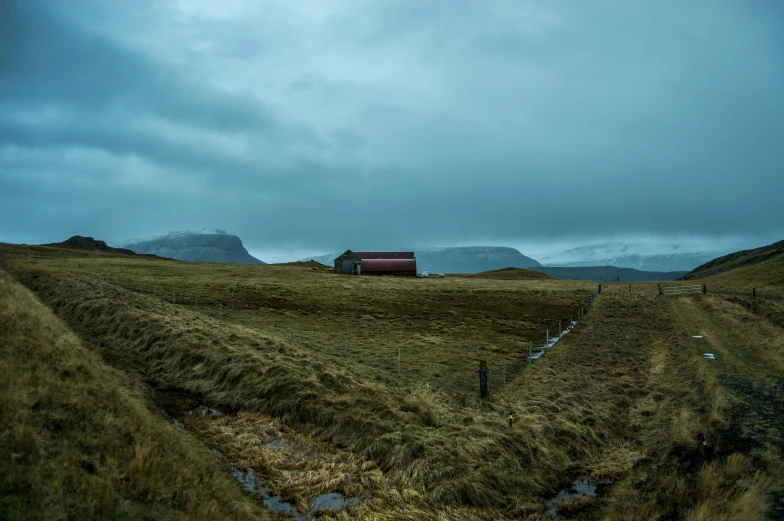 a grassy area with a red house and some mountains in the background