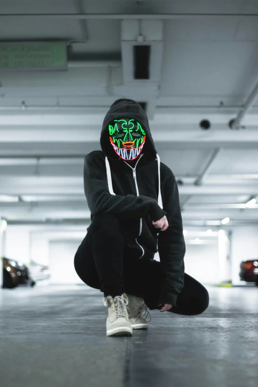 a person in a hoodie kneeling down in a parking garage