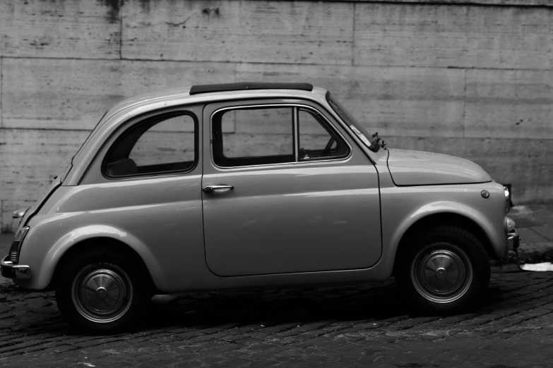 an old grey car sits near a stone wall