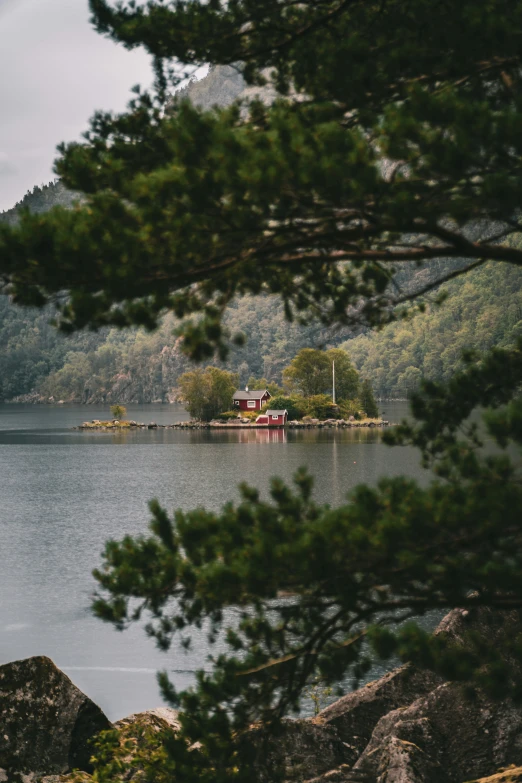 the house is in the middle of a large lake with a boat out front