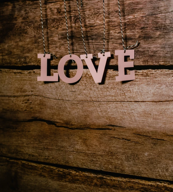 a wooden word spelling love hangs on a chain