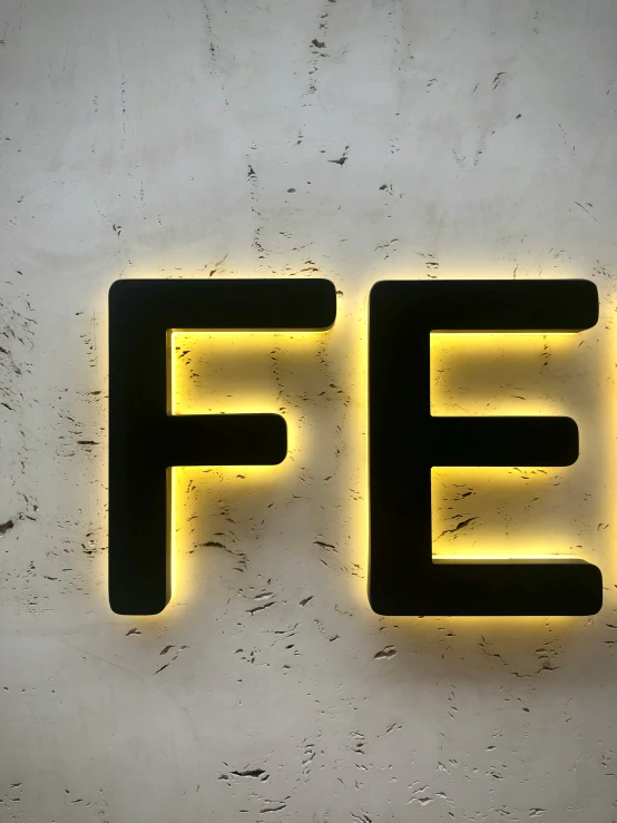 the word fe in a lighted yellow neon on a white surface