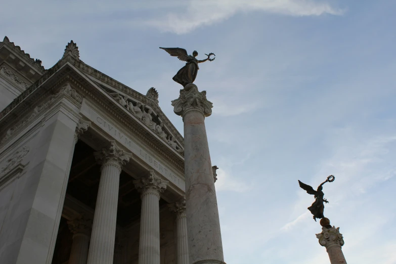 two stone statues stand near each other by an old building