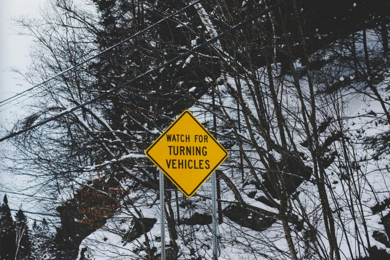 a yellow traffic sign sitting on top of a snow covered road