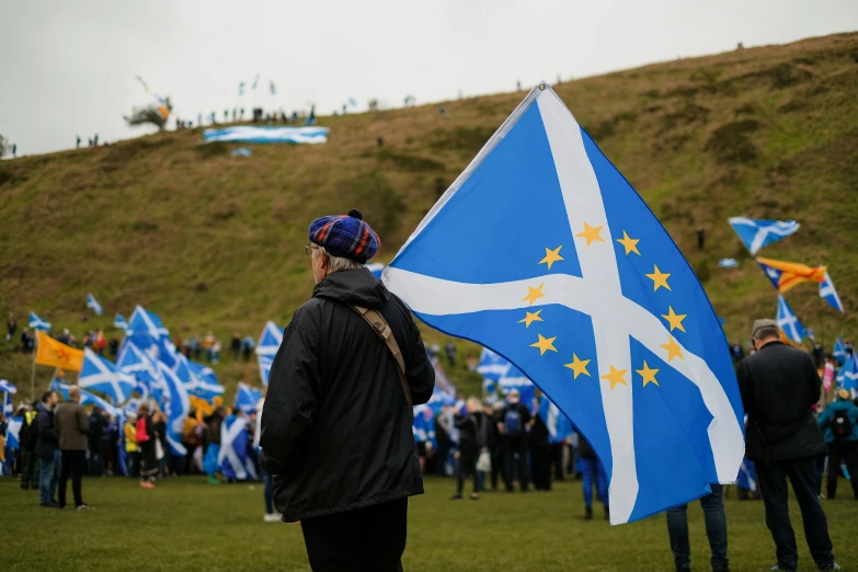 a man with a blue and white scottish flag is holding a flag