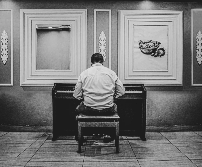 a black and white po of a man playing piano in a room