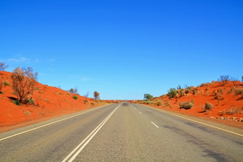 an empty road in the middle of red hills