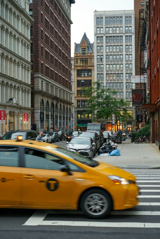 a yellow taxi drives through a city intersection