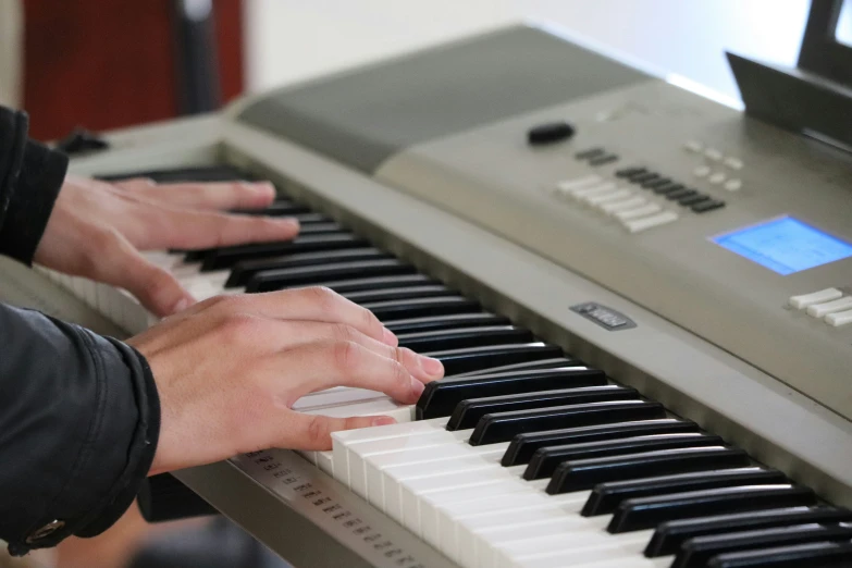 two people playing piano in front of a computer monitor