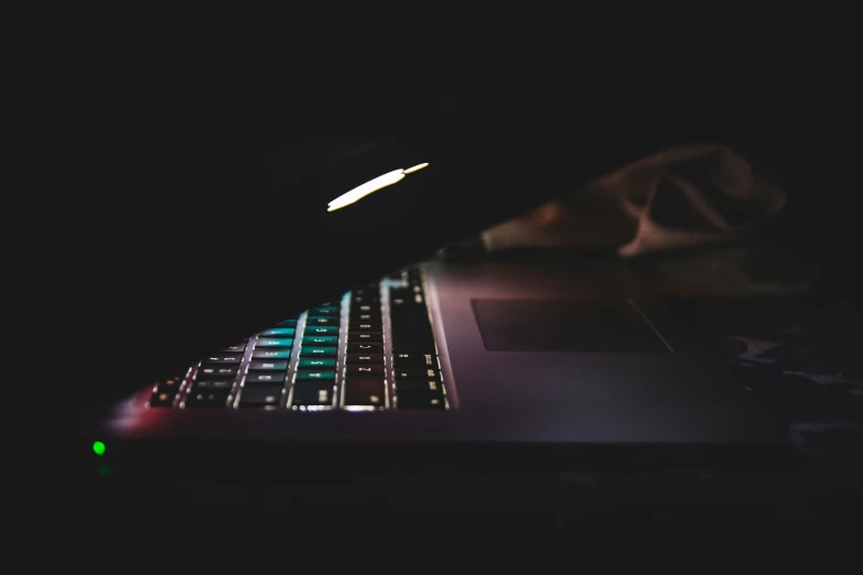 a laptop computer illuminated in a dark lit room