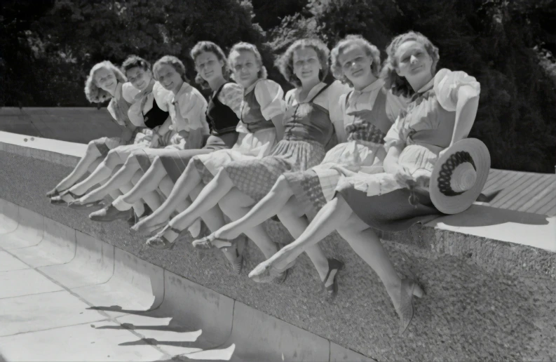 four women are posing for a po sitting on the edge of a wall