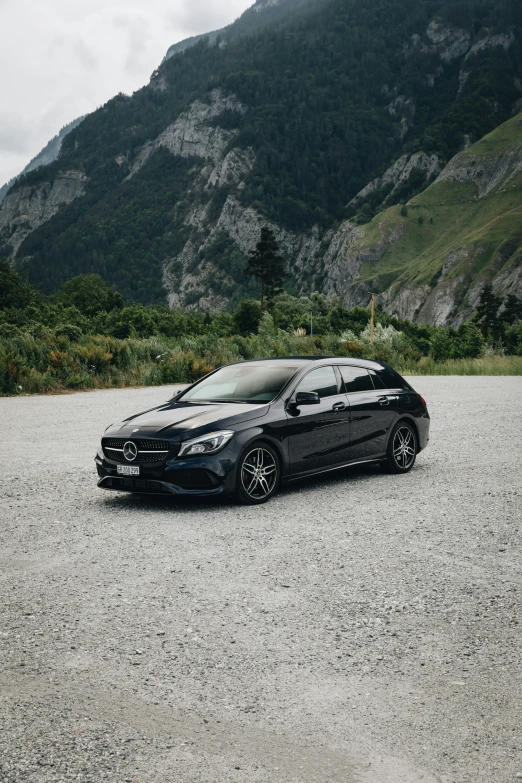 a car is sitting on the gravel near a mountain
