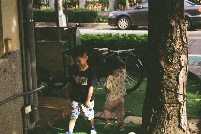 the two s stand near a tree with a bicycle on it