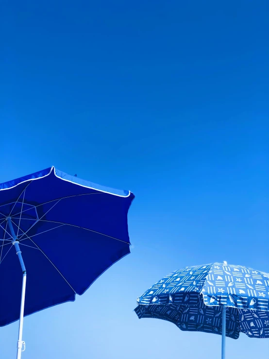 two blue and white umbrellas sitting in the air