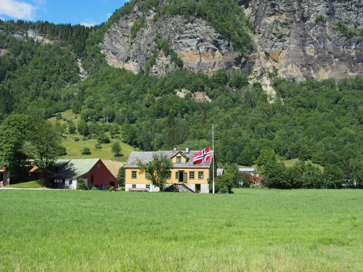 green pasture in front of houses with a mountain in the background