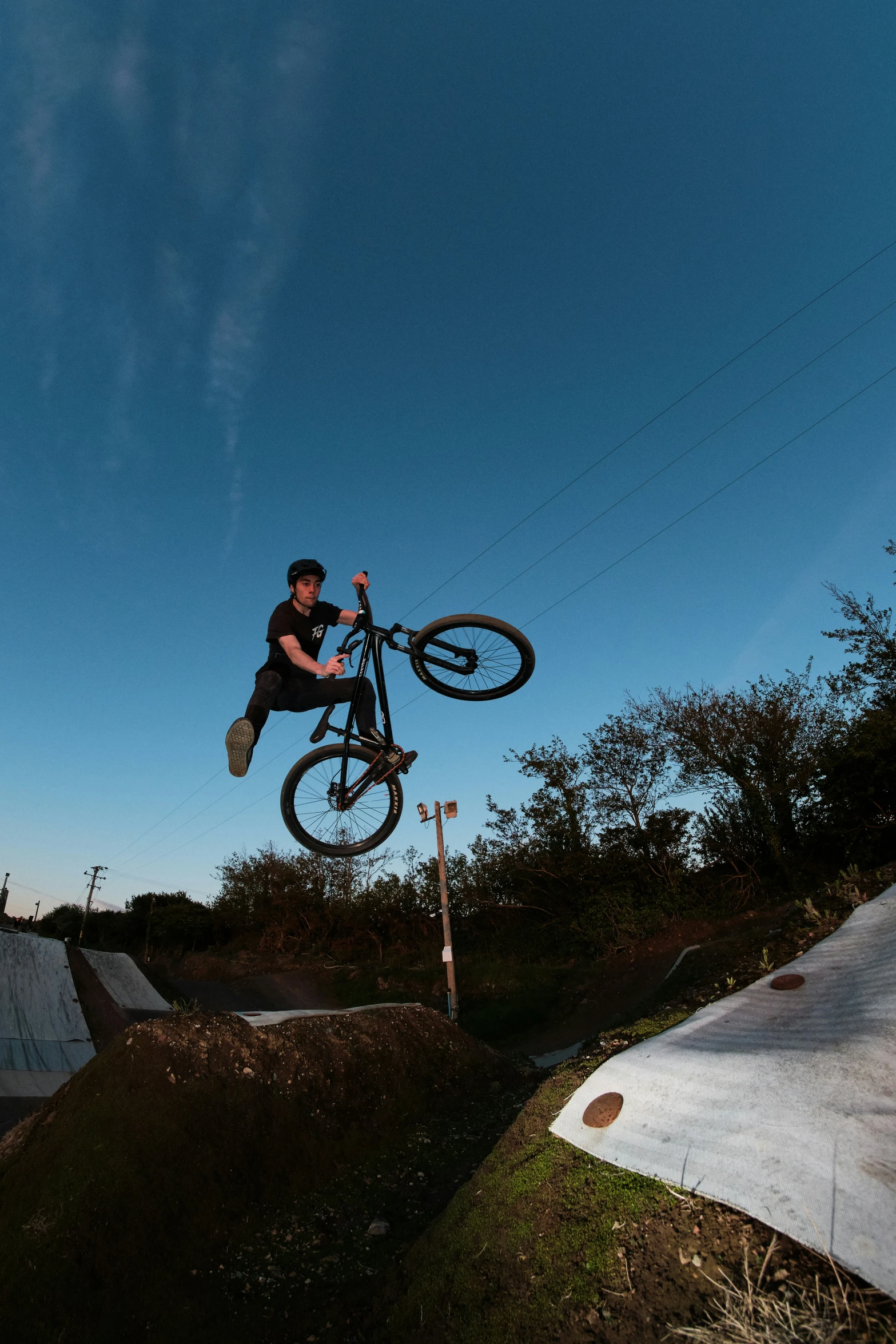 a man on a bike does a flip while jumping over two ramps