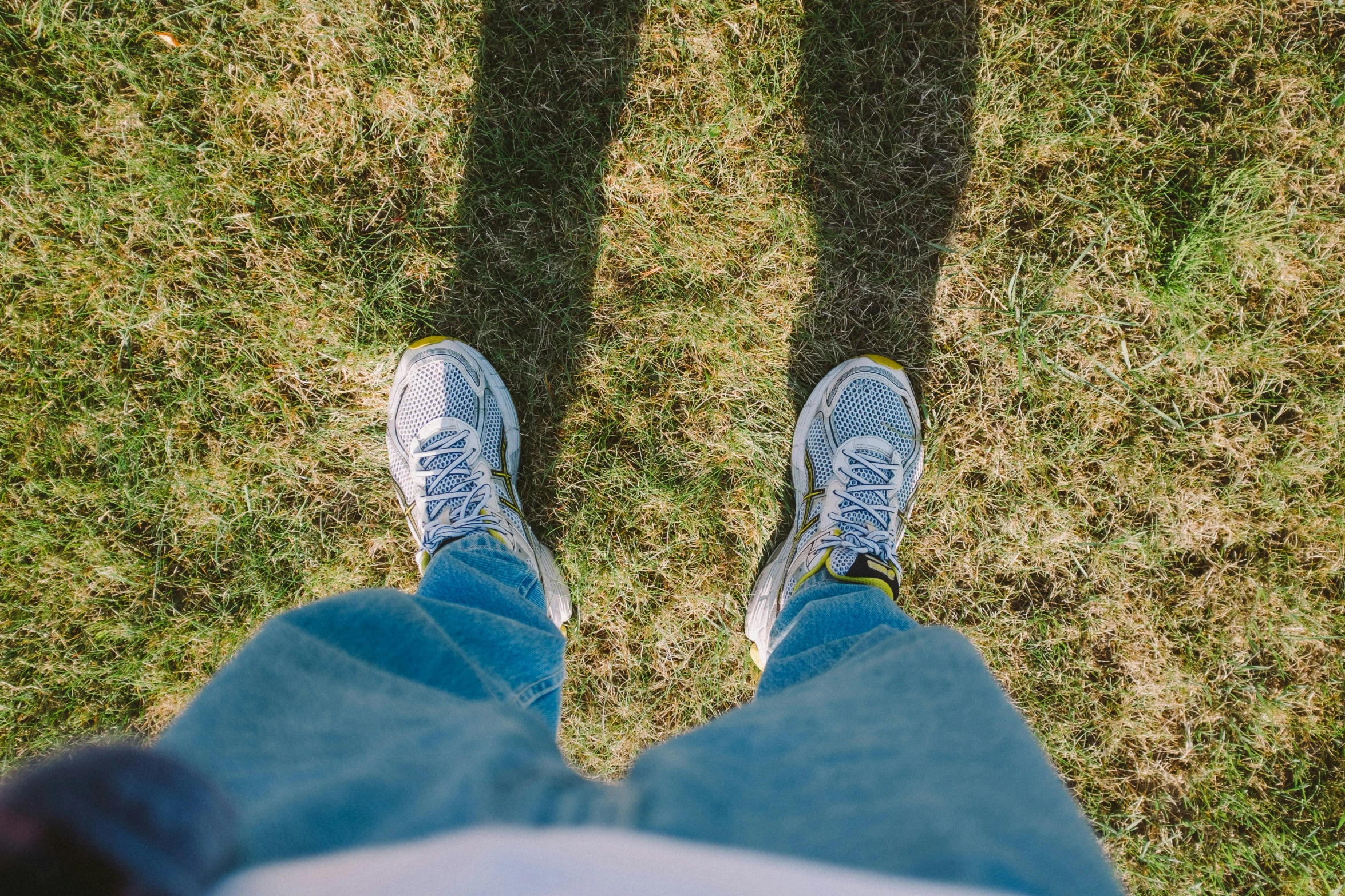 two feet in the grass one has blue shoes