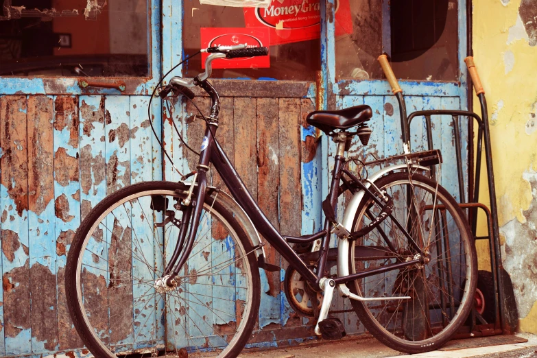 a bike leaning against the side of a building with a blue door