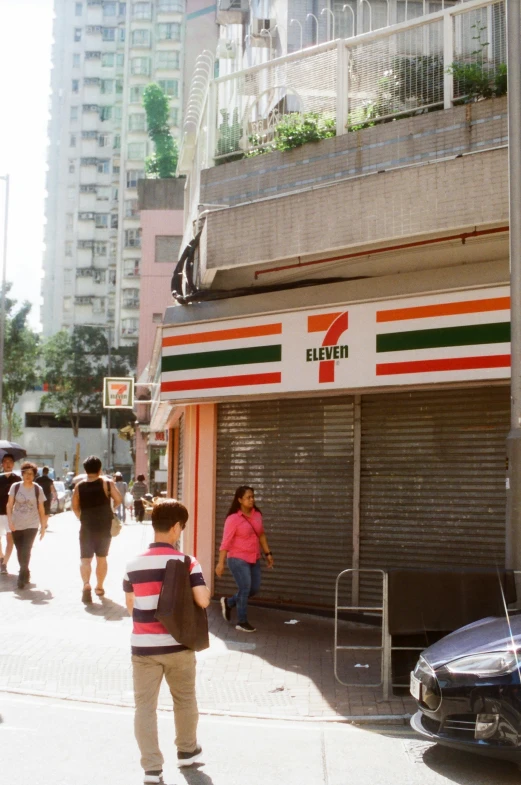 a number of people walk on the street near a closed store