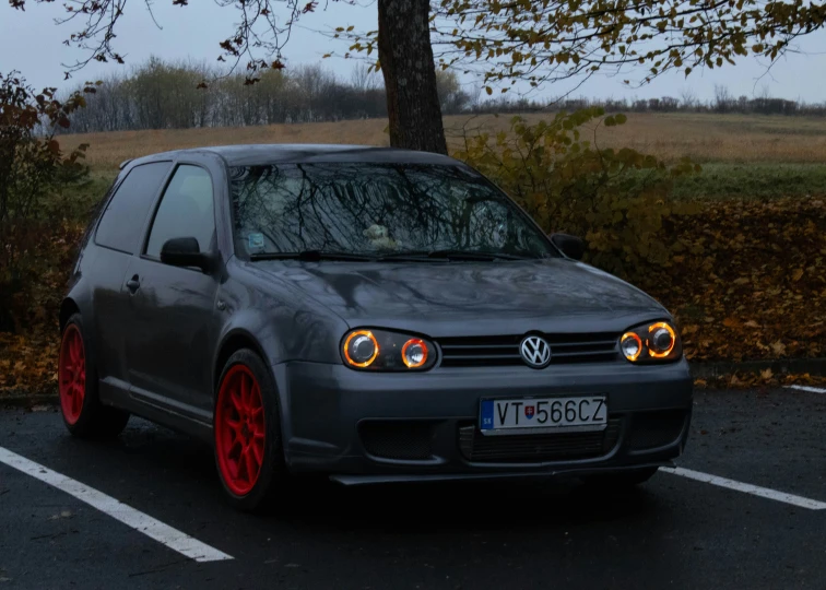 the volkswagen is parked near a tree with its red rims