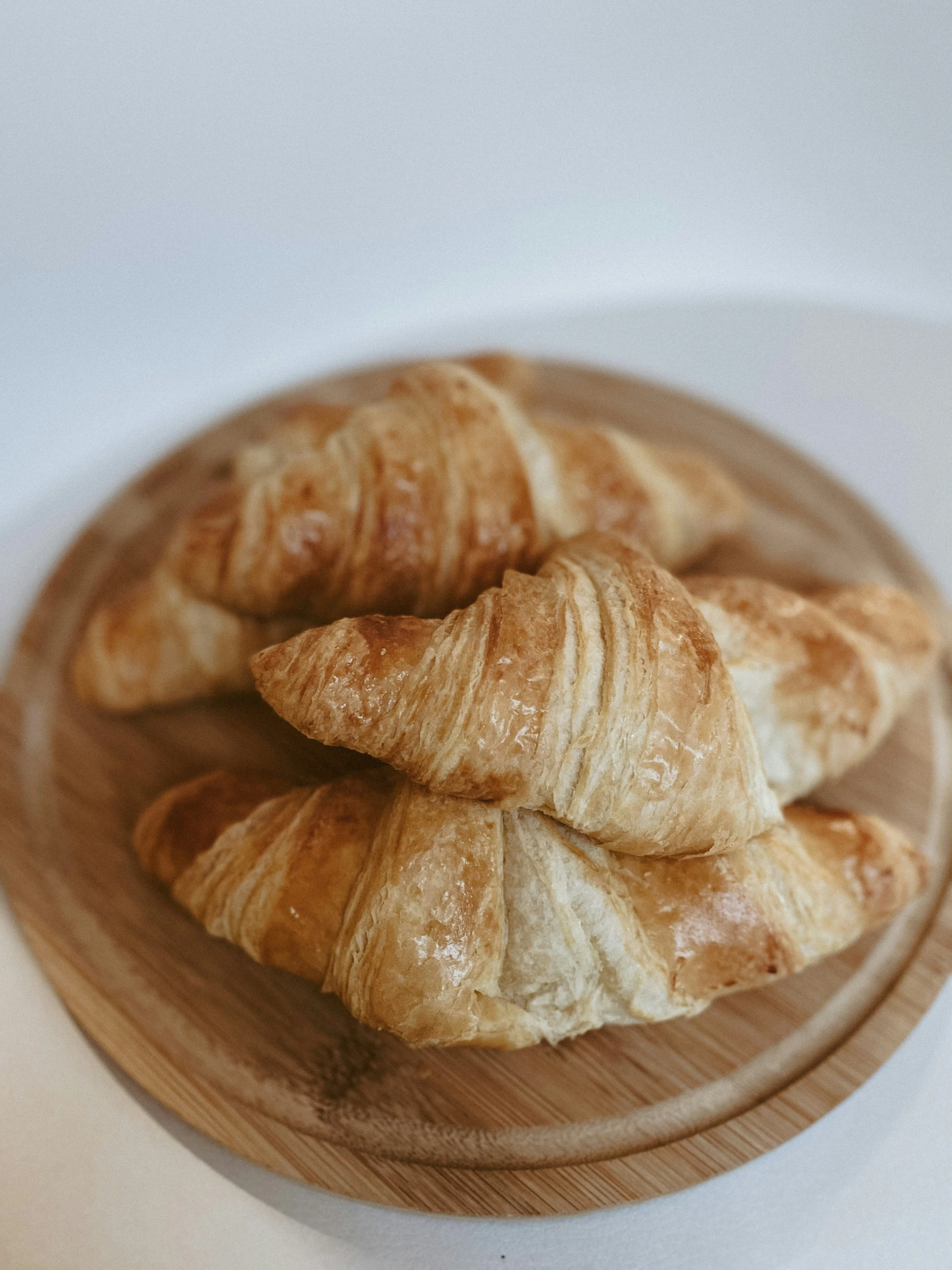 a wooden bowl filled with croissants sitting on top of a white counter