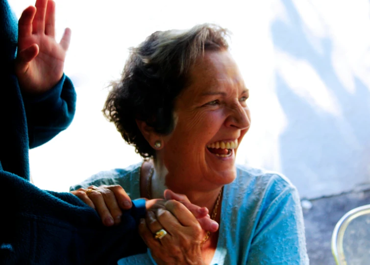 an older woman smiles as her fingers are up