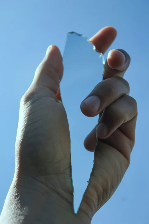 someone holds up a thin mirror to show their reflection