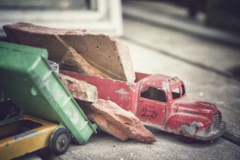 toys like a truck, tractor, and trailer are sitting on the concrete